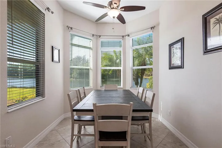 Dining area featuring a bay window with water scenery, recessed lighting, ceiling fan, and tile flooring