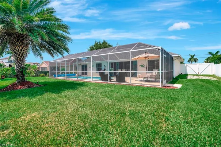 Rear view of house featuring glass enclosure, a patio, a lawn, and a fenced in pool
