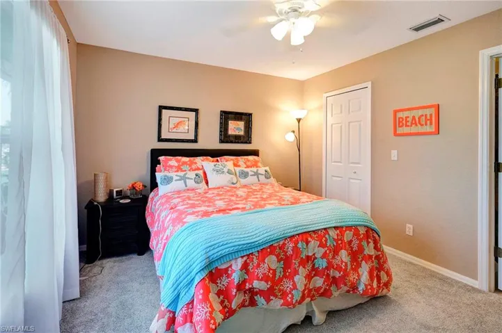 Bedroom with ceiling fan, light colored carpet, and a closet