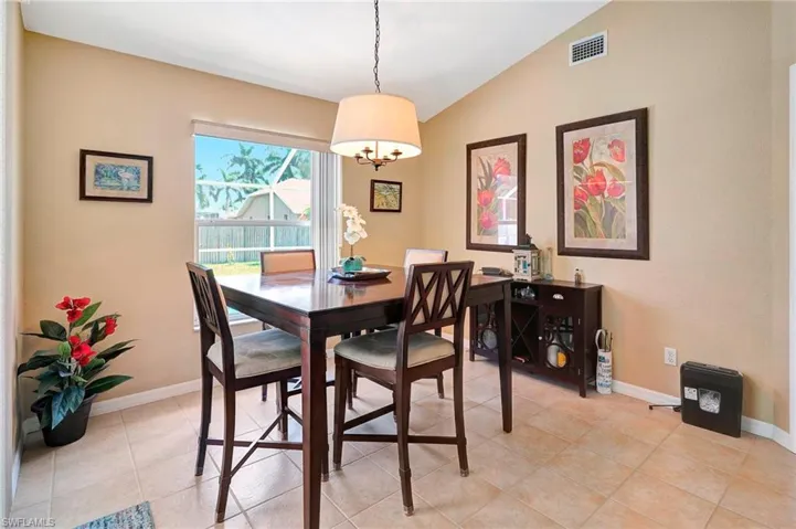 Dining space with lofted ceiling, light tile patterned flooring, and a chandelier