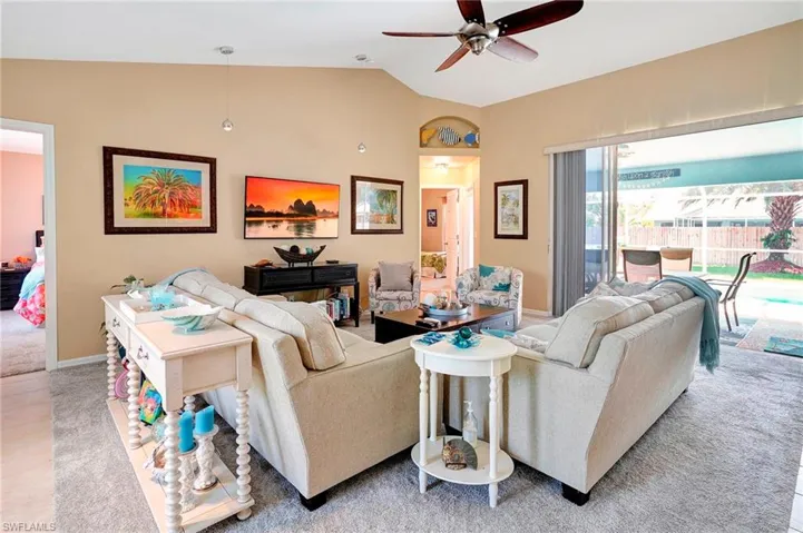 Carpeted living room with ceiling fan and vaulted ceiling