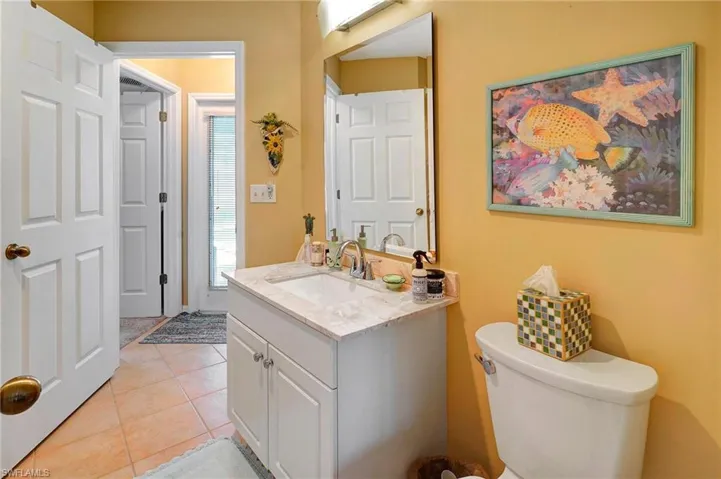 Bathroom featuring tile patterned flooring, plenty of natural light, toilet, and vanity