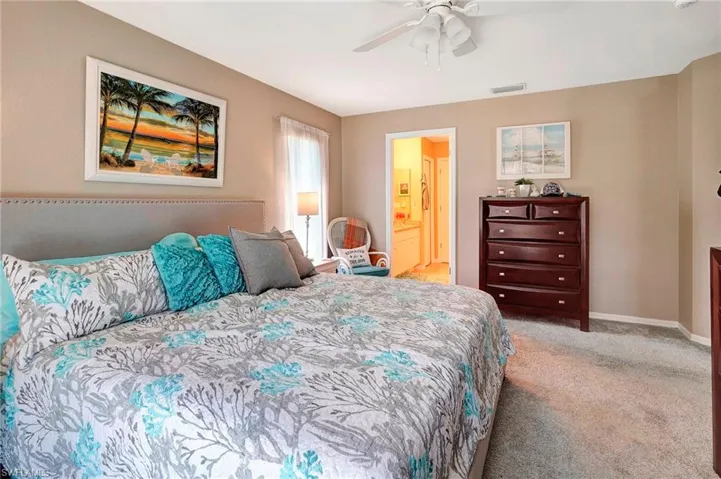 Carpeted bedroom featuring ceiling fan and ensuite bathroom