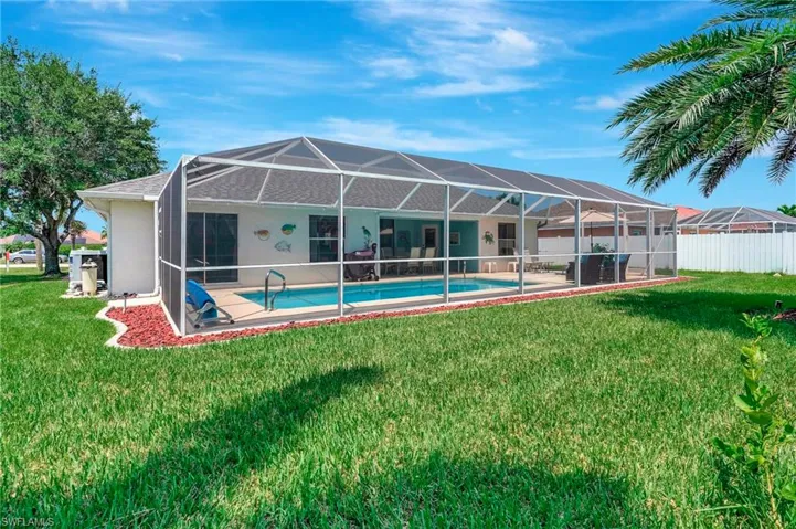 Back of house with a fenced in pool, a lawn, and a lanai