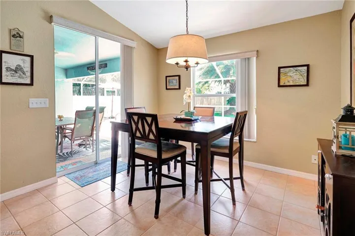 Dining room featuring light tile patterned floors and vaulted ceiling