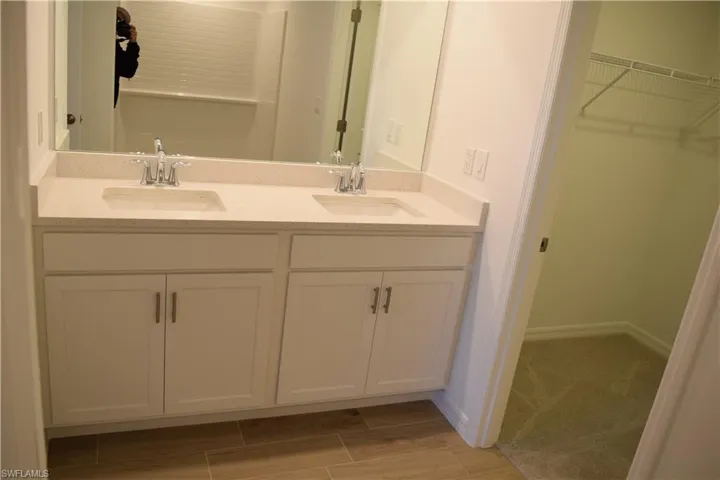 Bathroom featuring double vanity, a spacious closet, and wood tiled floors