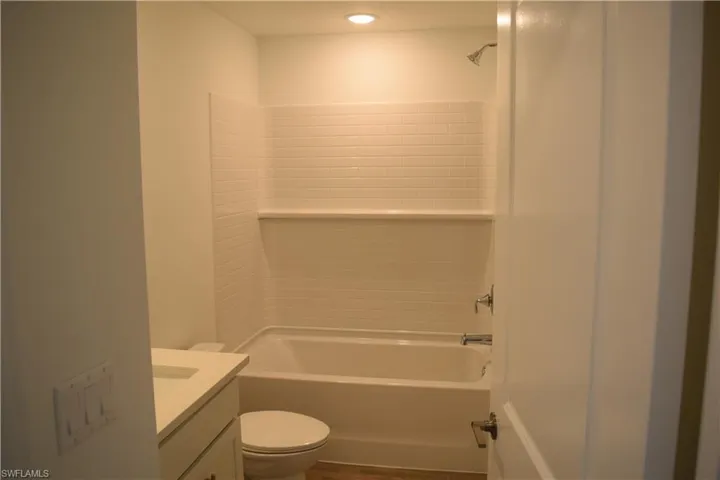 Bathroom featuring vanity, bathtub / shower combination, and dark wood-style flooring