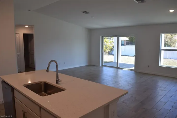 Kitchen with light stone counters, open floor plan, dishwasher, wood tiled floors, and recessed lighting