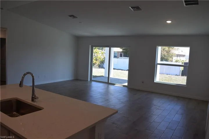 Kitchen with wood tiled floors, light stone counters, open floor plan, an island with sink, and recessed lighting