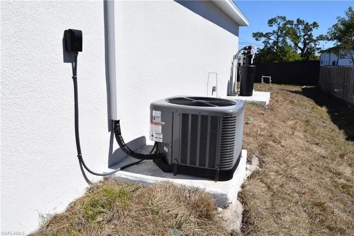 Exterior view of stucco siding and a water softener