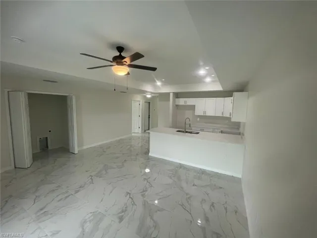 Kitchen featuring white cabinetry, kitchen peninsula, sink, and ceiling fan