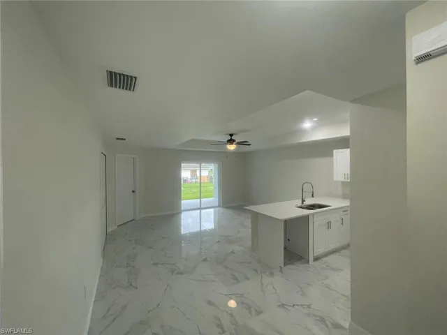 Kitchen featuring kitchen peninsula, sink, ceiling fan, and white cabinets