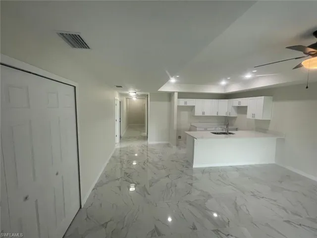 Kitchen with white cabinetry, kitchen peninsula, sink, and ceiling fan