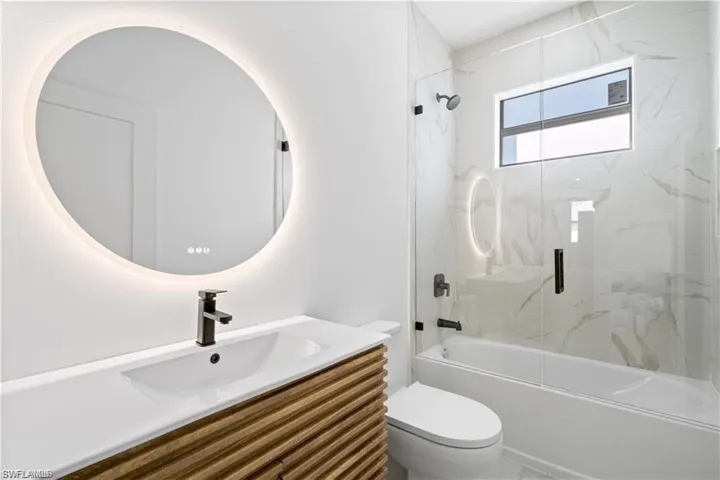 Full bathroom featuring vanity, toilet, and combined bath / shower with glass door