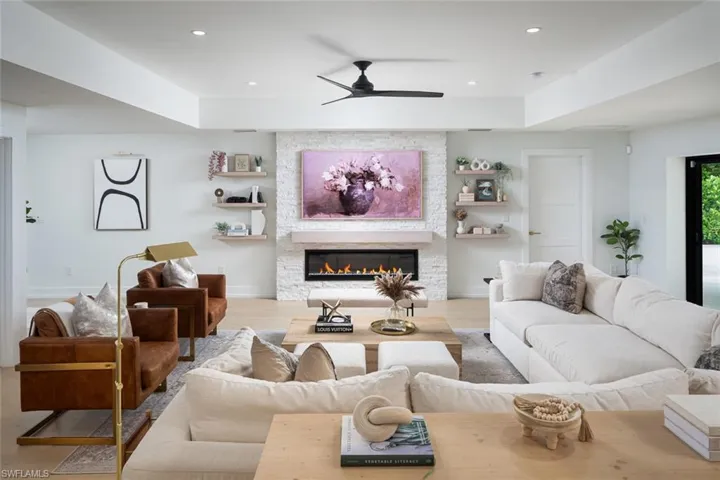Living room featuring a fireplace, a tray ceiling, hardwood / wood-style flooring, and ceiling fan
