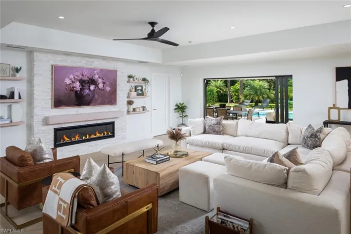 Living room with ceiling fan and a stone fireplace