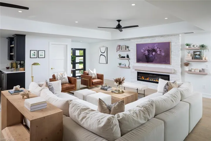 Living room with ceiling fan, a large fireplace, and light hardwood / wood-style floors