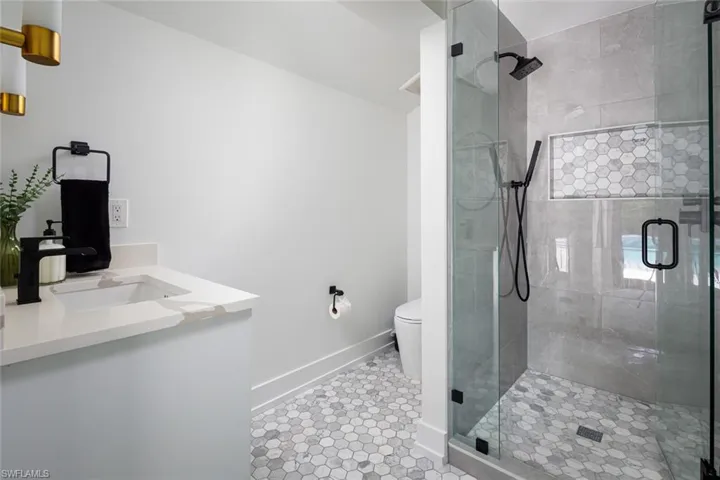 Bathroom featuring vanity, tile patterned flooring, toilet, and a shower with door