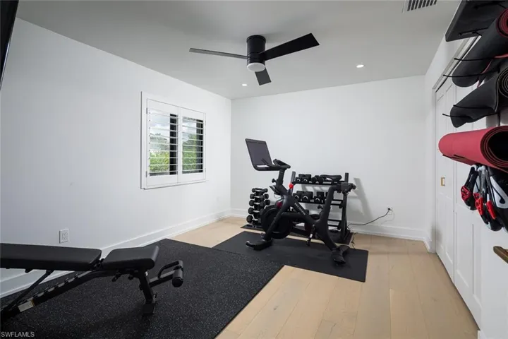 Workout room with light wood-style flooring and ceiling fan