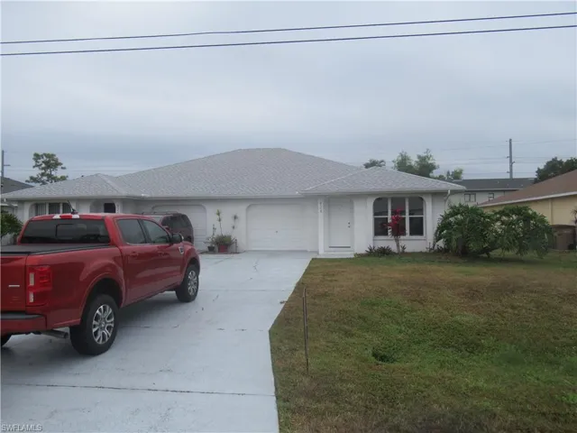 Ranch-style home featuring concrete driveway, a front lawn, an attached garage, and roof with shingles