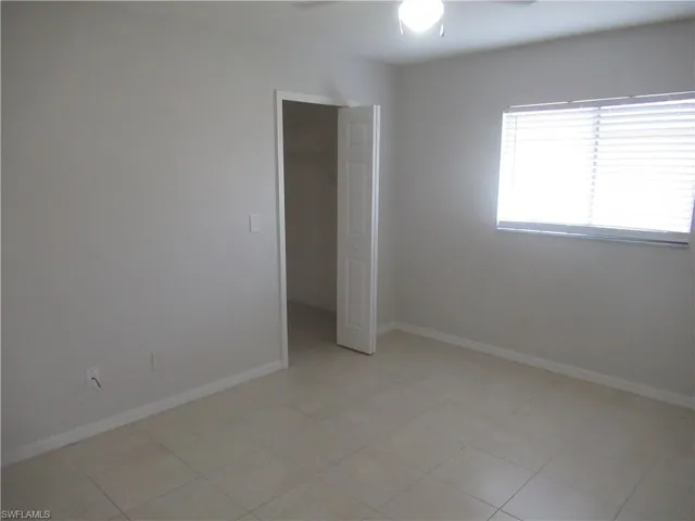 Empty room with ceiling fan and light tile patterned flooring