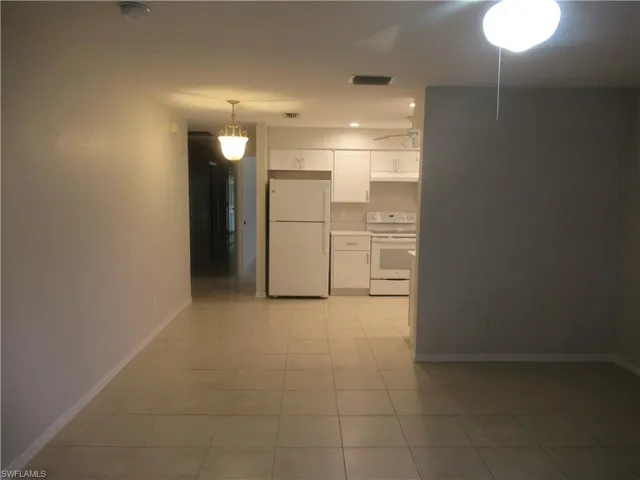 Kitchen with white cabinetry, white appliances, light countertops, hanging light fixtures, and light tile patterned floors