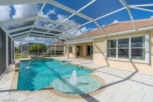 View of pool with pool water feature, a patio, an in ground hot tub, and glass enclosure