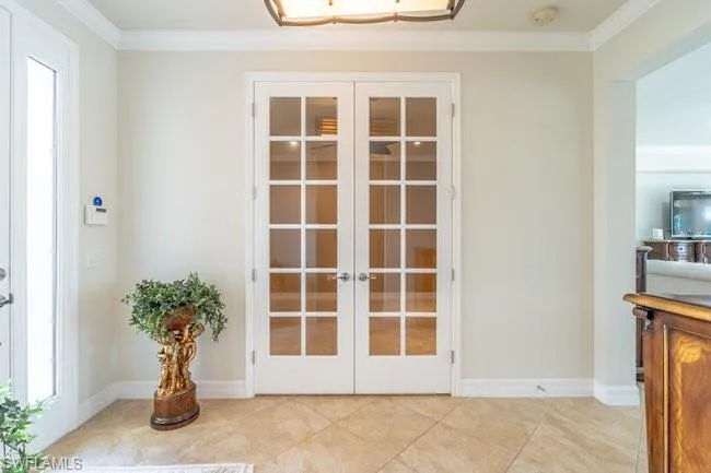 Doorway with ornamental molding, light tile patterned flooring, and french doors