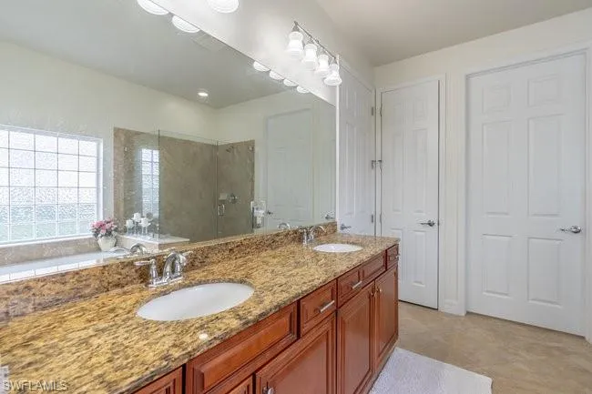 Bathroom with tile patterned floors, vanity, and a tile shower