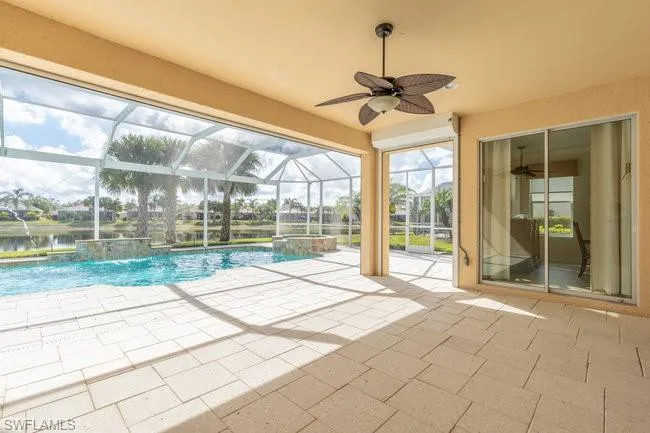 View of swimming pool featuring a lanai, ceiling fan, a water view, a patio area, and pool water feature