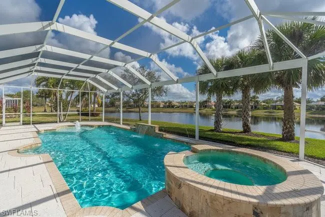 View of pool featuring an in ground hot tub, glass enclosure, and a water view