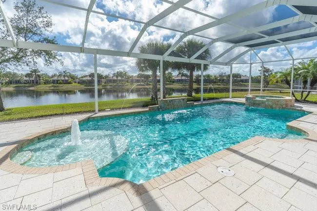 View of swimming pool with pool water feature, a water view, glass enclosure, an in ground hot tub, and a patio