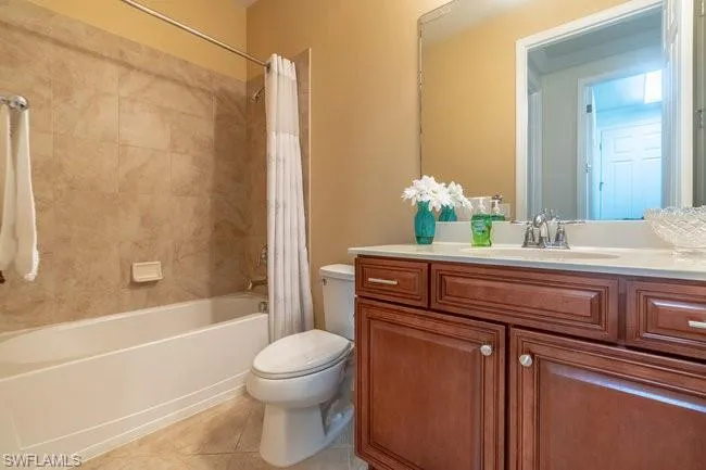 Full bathroom with vanity, toilet, tile patterned flooring, and shower / bath combo with shower curtain