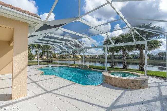 View of pool with a patio area, an in ground hot tub, pool water feature, and glass enclosure