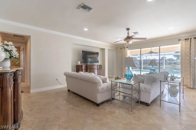 Tiled living room with ceiling fan and ornamental molding
