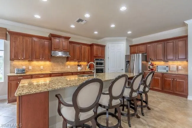 Kitchen with an island with sink, appliances with stainless steel finishes, a breakfast bar, and sink