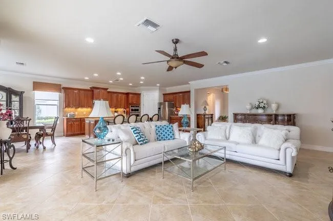 Tiled living room with ornamental molding and ceiling fan