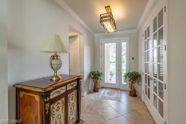 Entryway with crown molding, french doors, and light tile patterned flooring