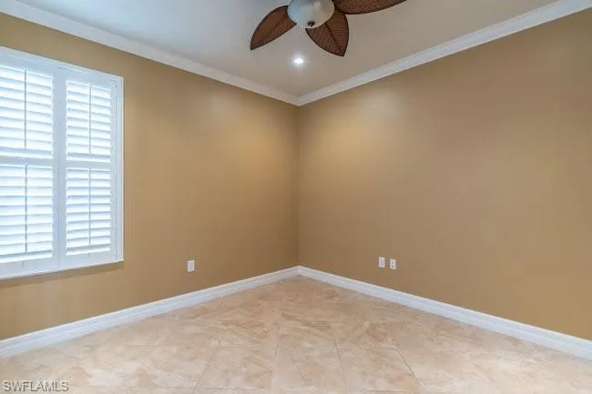 Empty room featuring crown molding, light tile patterned floors, and ceiling fan