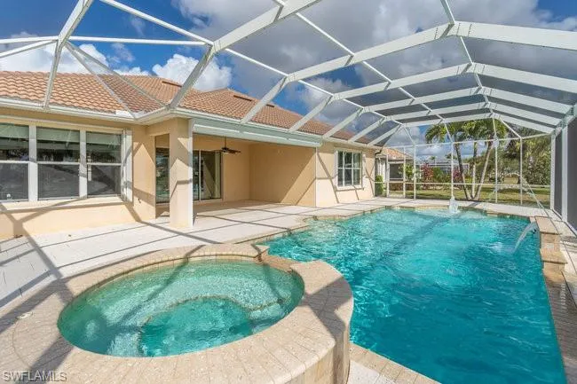 View of pool featuring an in ground hot tub, a lanai, pool water feature, ceiling fan, and a patio area