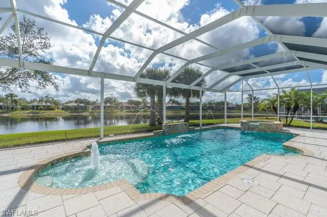View of swimming pool featuring pool water feature, a water view, an in ground hot tub, and glass enclosure