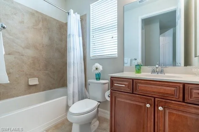 Full bathroom featuring vanity, shower / bathtub combination with curtain, tile patterned floors, and toilet