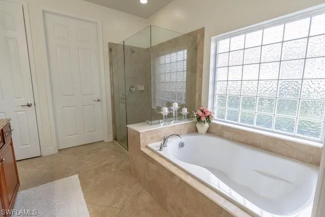 Bathroom featuring vanity, independent shower and bath, and tile patterned flooring