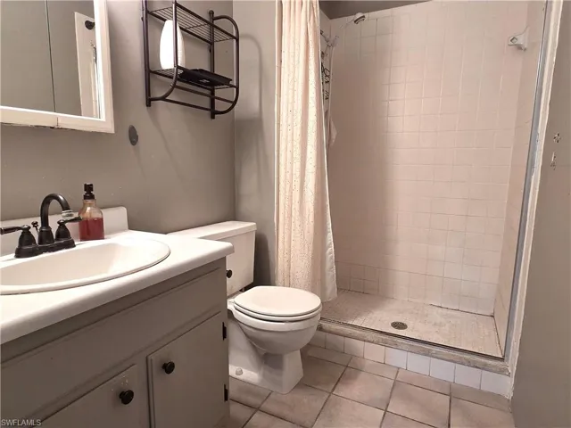 Bathroom featuring a vanity with an integrated sink, a toilet, and a tiled shower enclosure with a glass door
