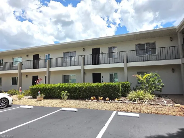 Two-story stucco building with a flat roofline and black balcony railings