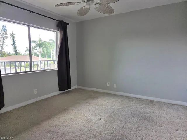 Expansive window offering a broad outdoor perspective, ceiling fan, neutral wall paint, and wall-to-wall carpeting