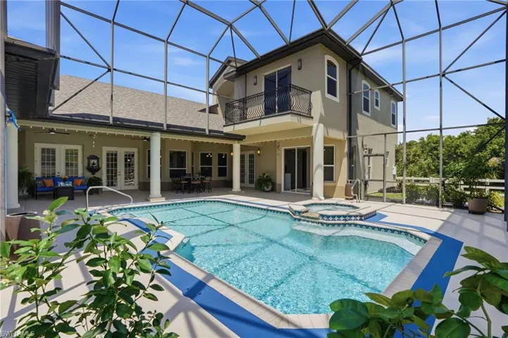 Screen-enclosed pool area featuring an integrated spa, featuring a second-story balcony