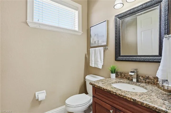 Bathroom vanity featuring an oval undermount sink, granite countertop, and wood-finish cabinetry