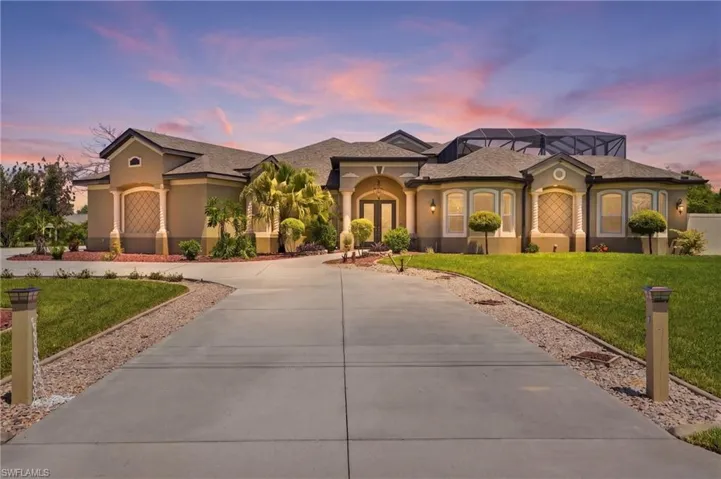 Stucco exterior featuring decorative window details and an expansive concrete driveway
