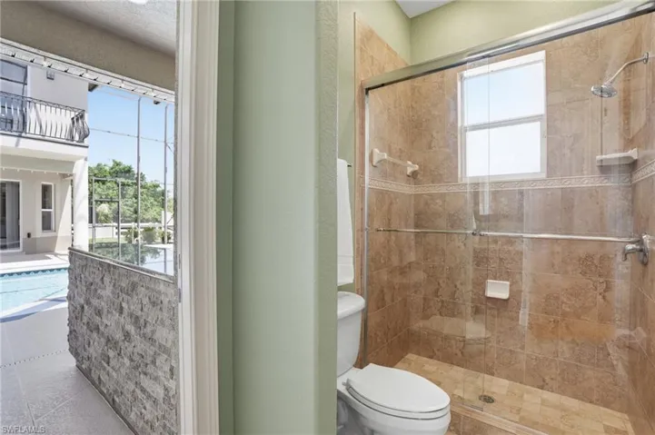 Tiled shower enclosure featuring a glass sliding door, built-in window, and a rain shower head